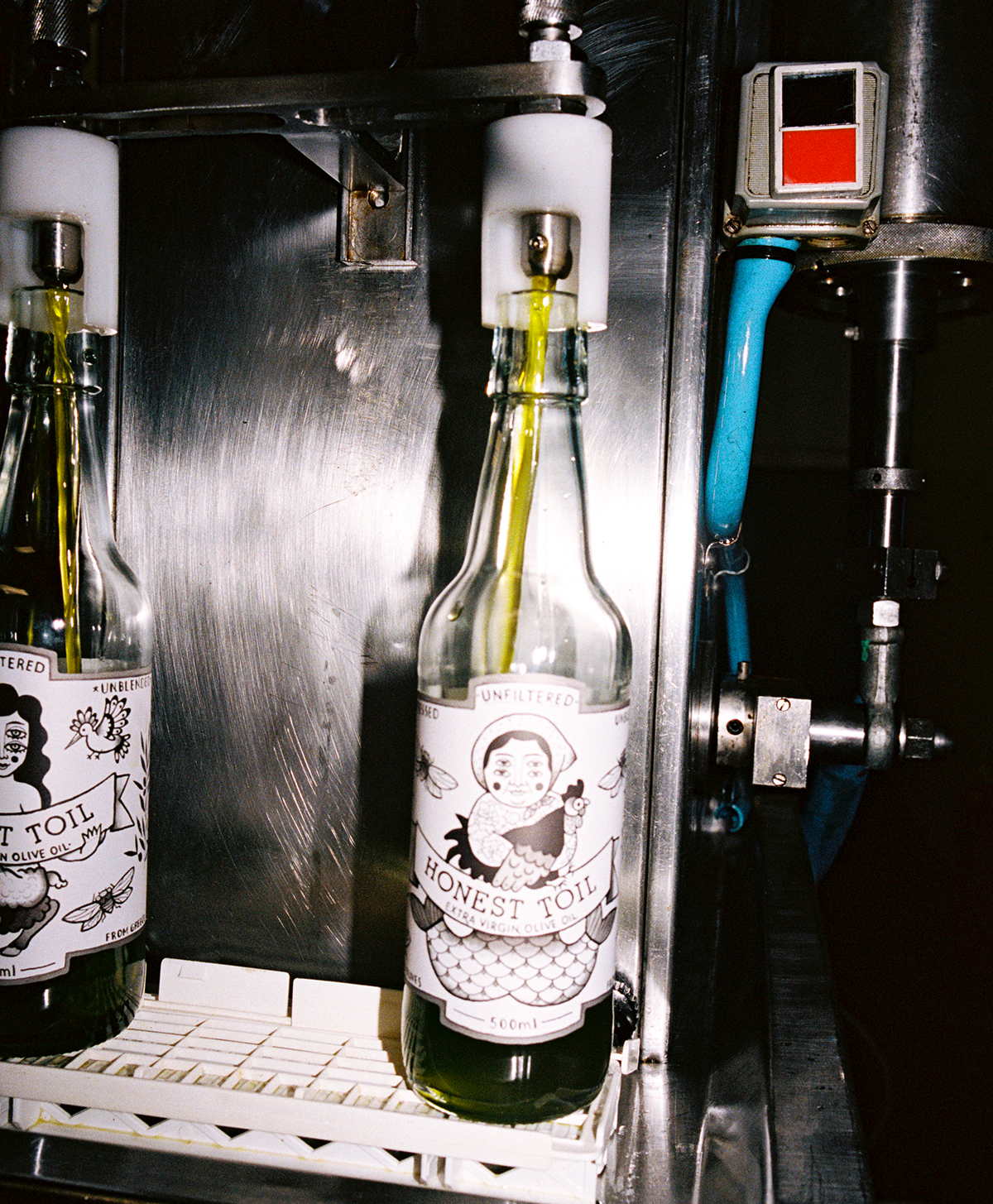 Bottle of honest toil olive oil with fresh raw oil being poured into it from the fresh harvest in greece