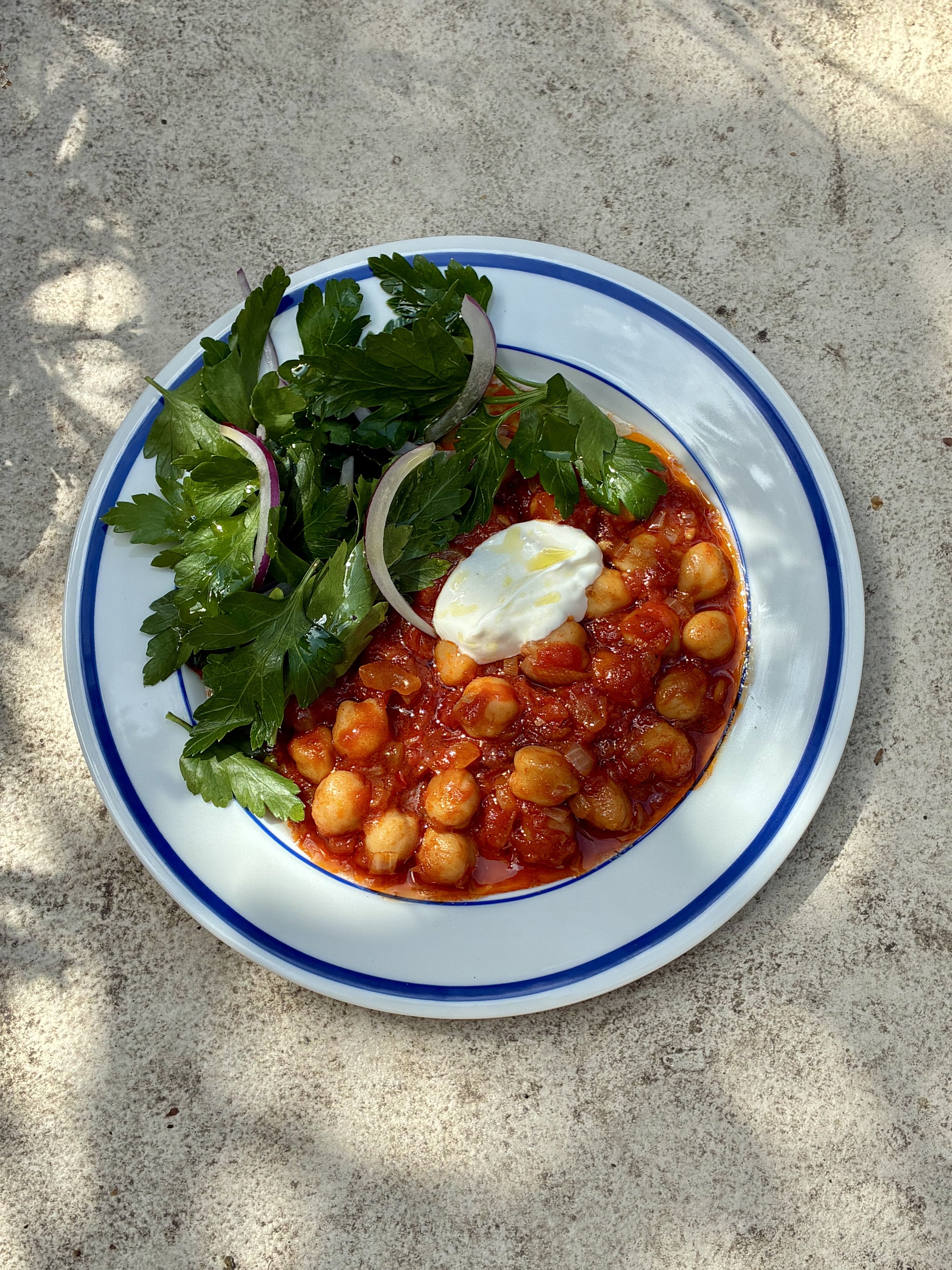 Chickpea and tomato stew topped with Greek yoghurt and olive oil, served with parsley salad