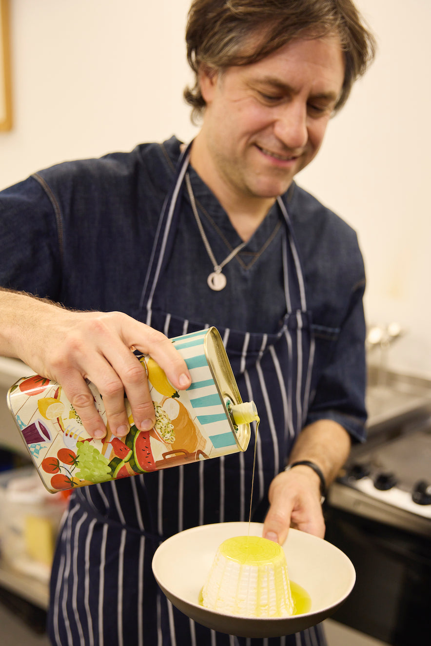 Person in a kitchen pouring a can of olive oil into a bowl